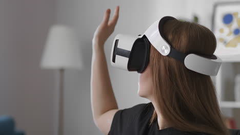 woman-is-using-head-mounted-display-touching-virtual-screen-by-hand-swiping-and-tapping-portrait-of-female-user-with-device-on-head-modern-technology-of-vr